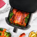 Szczegółowy przegląd frytkownicy TESLA AirCook Q60 XXL Pro podczas pieczenia całego kurczaka z warzywami, w przezroczystej szufladzie urządzenia.